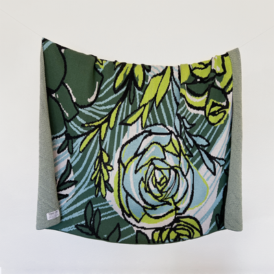 Vibrant Succulent Inspired Throw hanging on a line, showcasing bold turquoise, black, parrot green, hunter green, and gray colors, designed by Tuxberry & Whit, made of 100% cotton, eco-friendly, crafted in USA.