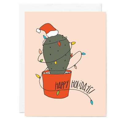 Hand Illustrated greeting card with cactus wearing red Santa at and colored Christmas lights. Hand lettered words read Happy Holidays in black. Light pink background.