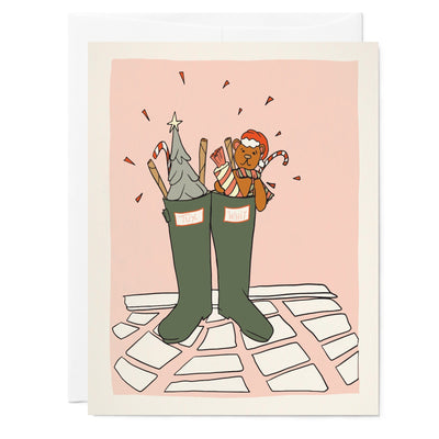 Illustrated holiday card featuring drawing of green rain boots filled with Christmas sweets sitting on tile floor with pink wall