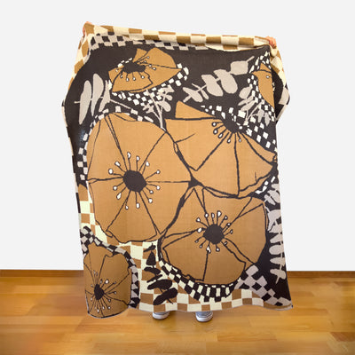 Person holding modern botanical artist designed throw displaying complete layered pattern system with poppy eucalyptus theme in neutral tones