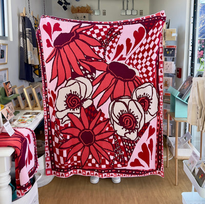 Full view of Valentine's cotton blanket with hearts and flowers in burgundy, red, pink, coral, and cream colors
