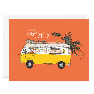 Hand illustrated greeting card featuring santa driving yellow retro VW van with palm tree and Christmas lights. Hand lettered words read Warmest Seasons greeting in white with bright orange red background.