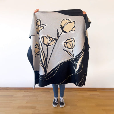 Person holding knitted blanket with neutral tulip floral design