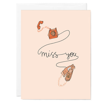 Hand illustrated greeting card with 2 landline phones connected with cord that says 'Miss you' in cursive writing. Black words light pink background